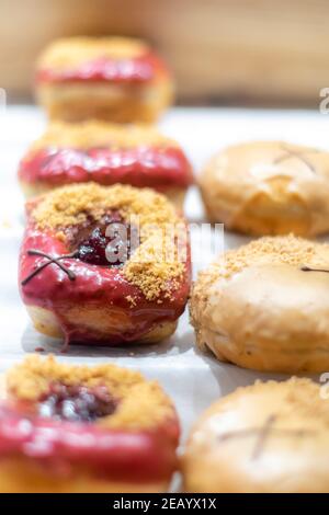 Bunte Donuts auf einem Tablett, süßer Zahnersatz für einen Donut-Tag, verschiedene Dognuts auf weißem Hintergrund mit geringer Schärfentiefe. Stockfoto