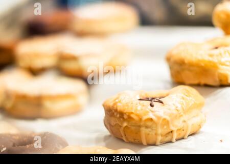 Bunte hausgemachte Donuts auf einem Tablett, süße Zahnbehandlung für einen Donut-Tag, verschiedene Dognuts auf weißem Hintergrund mit geringer Schärfentiefe. Stockfoto