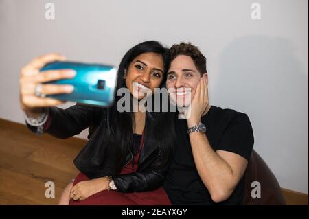 Fröhliche junge Paar nehmen ein Selbstporträt mit lustigen Gesicht zu Hause sitzen auf Bohnenbeutel. Stockfoto