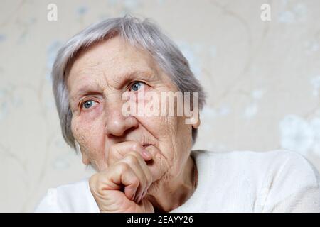 Ältere Frau mit friedlichem Ausdruck dachte über etwas nach. Weiblich mit grauen Haaren und faltiger Haut, Konzept der Erinnerungen, Alter Stockfoto
