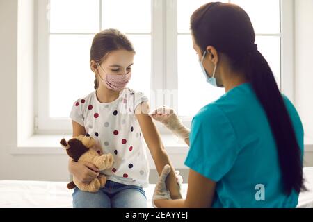 Krankenschwester desinfiziert die Haut am Arm des Kindes, bevor sie Covid-19 oder gibt Grippeimpfstoff-Injektion Stockfoto