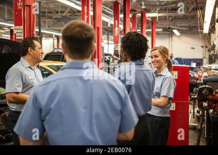 Team von Mechanikern, die an einem Auto arbeiten, besprechen ein Problem In einer Autowerkstatt Stockfoto