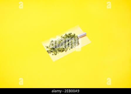 Marihuana-Gelenk aus zwei Arten von Cannabiszubereitungen: Haschisch und Unkrautknospen. Hochwertiges Marihuana Joint Isolat auf gelbem Hintergrund. Stockfoto