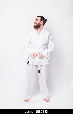 Portrait des jungen Ausbilders Mann trägt Taekwondo Uniform lächelnd und Blick zur Seite. Stockfoto