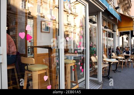 PARIS, FRANKREICH - 14. FEBRUAR 2019: Die Menschen sitzen auf der Terrasse und im Inneren des Cafés im lateinischen Viertel, dekoriert für den Valentinstag mit Herzen. Stockfoto