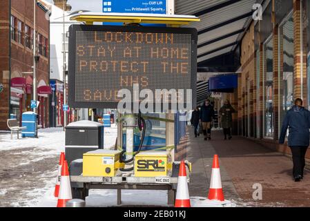 Southend on Sea, Essex, Großbritannien. Februar 2021, 11th. Über Nacht fiel auf Southend weiterer Schnee. Die Leute gehen auf der unruhigen High Street und passieren COVID 19 Lockdown Warnung Matrix Zeichen. Stockfoto