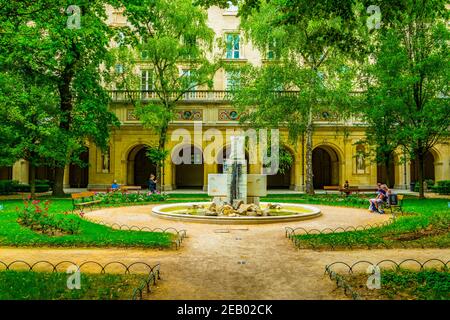 LYON, FRANKREICH, 22. JULI 2017: Die Menschen entspannen sich auf einer Bank im Park des Palastes von Saint Pierre in Lyon, Frankreich Stockfoto