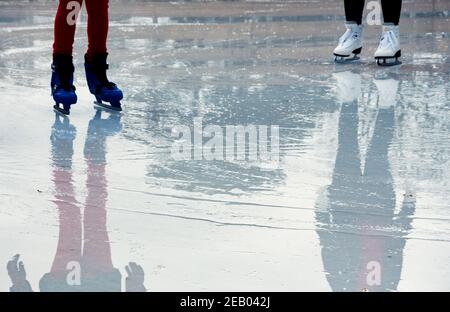 Zwei Mädchen beim Schlittschuhlaufen auf der nassen Eisbahn. Anfänger und professioneller Skater. Zielerreichungskonzept. Reflexion. Abstrakter Winterurlaub Stockfoto