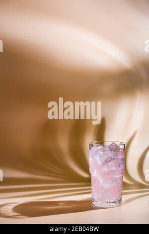Sommerliche Erfrischung rosa Getränk mit Eis. Cocktail aus hellrosa Rosen auf einem rosa Hintergrund mit hellen Schatten Stockfoto