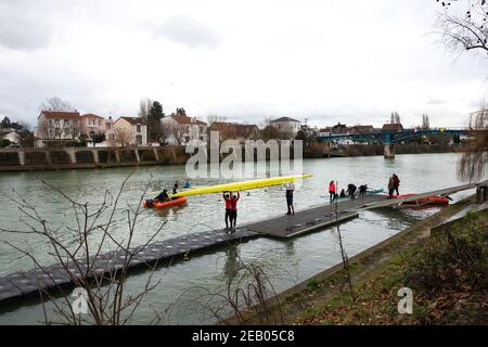 ILE-DE-FRANCE, FRANKREICH - 26. JANUAR 2019: Ausbildung von Juniorrudern am Fluss Marne. Boys tragen und bekommen das Boot im Wasser. Stockfoto