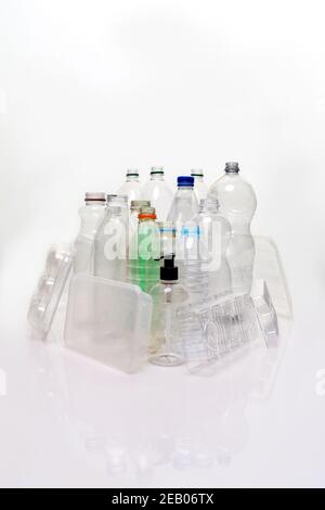 Eine Sammlung von Haushaltskunststoff auf Basis von Material auf weißem Hintergrund mit Reflexion aufgenommen. Flaschen, Lebensmittelschalen, Pumpbehälter bereit zum Recycling. Stockfoto
