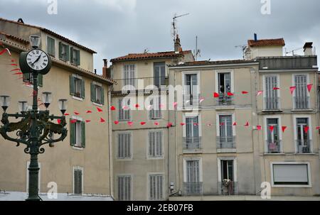 Traditionelle Häuser mit den typischen hölzernen grauen Fensterläden und roten Festbannern in Aubagne, Bouches-du-Rhône, Provence Frankreich. Stockfoto
