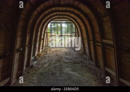 Verlassene Minenausfahrt, unterirdischer Tunnel mit Holzwänden, Eisenstangen und Blick nach draußen Stockfoto