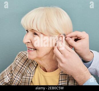 Schwerhörigkeit bei älteren Menschen, Hörlösung. Arzt, der Hörgerät auf das Ohr älterer Frauen einführt, Nahaufnahme Stockfoto