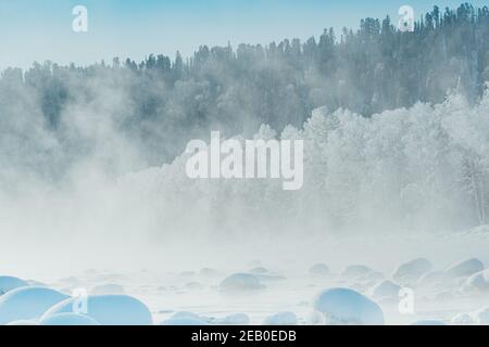 Winter Fluss mit frostigen Nebel über dem Wasser. Schneebäume am Ufer. Stockfoto