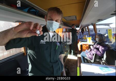 Der Sanitäter Andrew Parker bereitet den Impfstoff in einem Reisebus vor der medizinischen Praxis Culloden in der Nähe von Inverness, Schottland, vor, die vom Scottish Ambulance Service als mobiles Impfzentrum für Coronaviren verwendet wird. Bilddatum: Donnerstag, 11. Februar 2021. Stockfoto