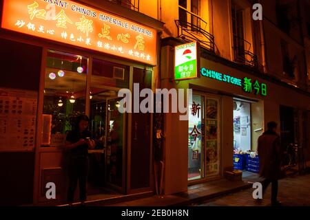 PARIS, FRANKREICH - 19. OKTOBER 2019: Städtische Abendszene in einem der ältesten asiatischen Viertel von Paris (3rd Bezirk). Leute kaufen in den lokalen Geschäften ein; essen im po Stockfoto