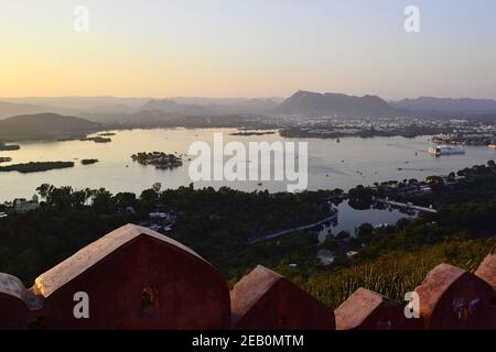 Panoramablick auf den Pichola See und Udaipur Stadt bei einem Sonnenuntergang. Blick von einem Hügel Karni Fort Festungsmauer, Rajasthan, Indien Stockfoto