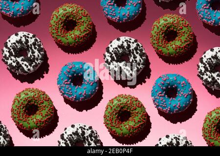 Verschiedene Donuts mit Krume auf rosa Hintergrund Stockfoto