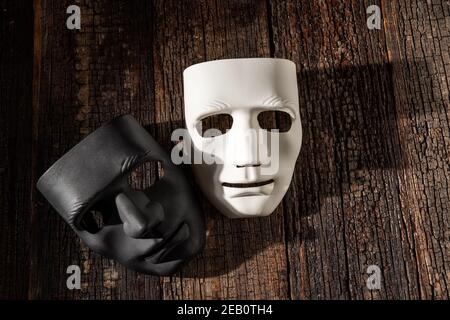 Schwarz-weiße Masken auf einem hölzernen Vintage-Hintergrund, Symbol für Anonymität und Theater. Bei Nahaufnahme von Schatten, Kopierbereich Stockfoto