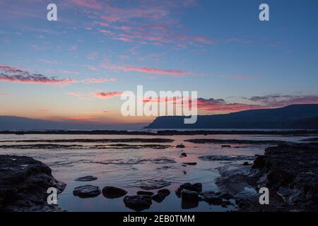 Blick auf den Sonnenaufgang vom felsigen Strand in Robin Hood's Bay An der Yorkshire Coast mit Blick auf Ravenscar Stockfoto