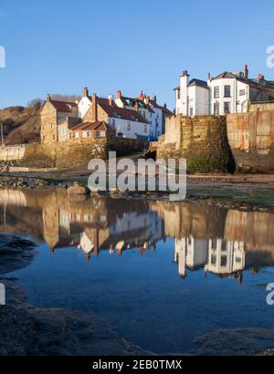 Blick auf die Bootsanlegestelle und das Dorf Robin Hood's Die Bucht spiegelt sich in einem ruhigen Felsenpool wider Stockfoto