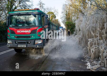 Iver, Buckinghamshire, Großbritannien. 11th. Februar 2021. Ein selbstsüchtiger LKW-Fahrer spritzt Wasser auf den Bürgersteig. Bäume neben einer Straße in Iver wurden in einen magischen Eiszackturm verwandelt, während das vom vorbeifahrenden Verkehr aufgeworfene Hochwasser gefroren bleibt und wie ein Filmset aussieht. Die Temperaturen unter dem Nullpunkt sind so eingestellt, dass sie bis zu diesem Sonntag andauern. Quelle: Maureen McLean/Alamy Live News Stockfoto
