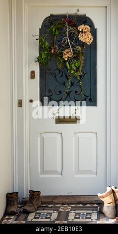 Wanderschuhe vor der Haustür eines gehobenen Vorstadthauses während der Covid-Absperrung in Wales. Stockfoto