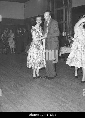 1950s, historisch, ein Mann und eine Dame tanzen zusammen auf einer Party auf einem Holzboden in einem Veranstaltungsraum in einem Hotel, England, Großbritannien. Der Mann trägt einen Anzug und Krawatte und die Dame ein langes Kleid mit Blumenmuster, das an die weibliche Mode der Zeit anmutet. Musikalisch war es die Zeit des Swings, der Big Band und des Skiffles, des Vorläufers zum Rock and Roll. Stockfoto