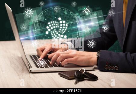 Business Hand arbeiten an der Börse mit Iota Symbole kommen Aus dem Laptop-Bildschirm Stockfoto