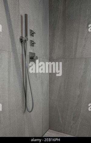 Moderner Chrom-Duschkopf im Badezimmer auf grauem Marmorboden an der Wand. Luxuriöse Duschkabine. Luxuriöser heller Hintergrund für Interieur und Design Stockfoto