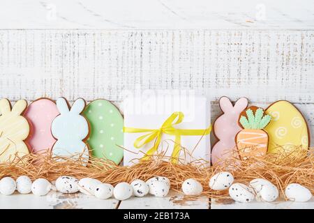 Ostern Grußkarte mit bunten Kaninchen, Eier, Hühner und Karotten Lebkuchenkekse auf weißem Holz alten Hintergrund mit Kopierraum. Modell. Ba Stockfoto