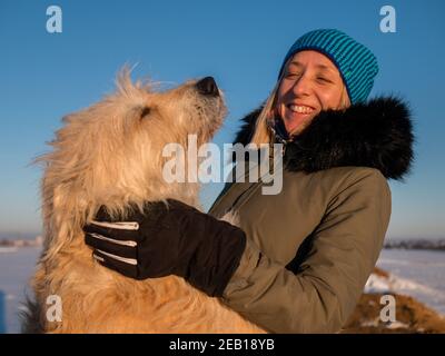 Winter warme blonde Frau mit ihrem Schafhund und blauen Himmel Hintergrund Stockfoto