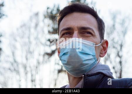 Weißer Mann mittleren Alters trägt eine medizinische Maske draußen in einem Sport-Outfit Stockfoto