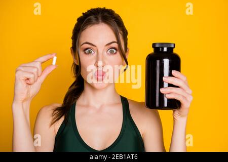 Close-up-Porträt von attraktiven lustigen Mädchen halten in den Händen Medikamente Energie Heilmittel pout Lippen isoliert über hellgelb Farbiger Hintergrund Stockfoto