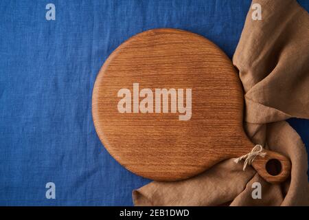 Food Hintergrund mockup mit runden Holz Schneidebrett auf hell Blaue Leinentischdecke aus Textil Stockfoto