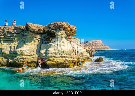 AGIA NAPA, ZYPERN, 30. AUGUST 2017: Touristen springen von den Meereshöhlen bei Cap greco im Südosten zyperns ins mittelmeer Stockfoto