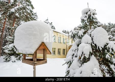 Schönes Vogelhaus aus Holz mit einem Dach, das von Schnee bedeckt ist Ein Wald oder Park im Winter Stockfoto