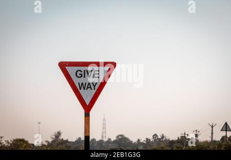 Indische Straße obligatorisches Zeichen, das angibt, Platz für den laufenden Verkehr zu geben. Schild, das beim Zusammenführen zurück auf die Straße angibt, dass der Weg frei wird Stockfoto