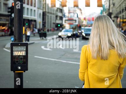 Nicht erkannte Person, die an einer Kreuzung wartet. Wartenschild leuchtet auf. Stockfoto