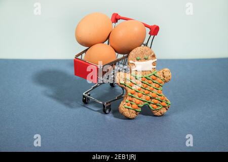 Ein Lebkuchenmann in einer Schutzmaske kauft Eier im Supermarkt zum Frühstück. Stockfoto