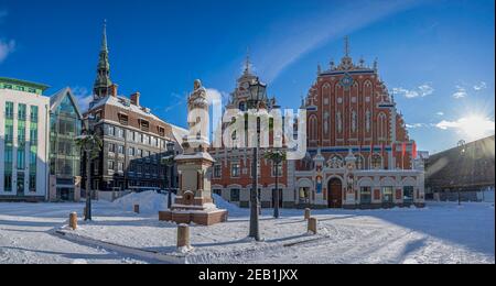 Rathausplatz während sonnigen Winterschneetag in Riga, Lettland. Blick auf das verschneite Haus der Schwarzköpfe und Rolands Statue in der Altstadt von Riga. Stockfoto