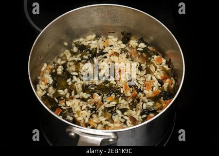 Risotto Kochen in offener Metallpfanne auf Elektroherd Stockfoto