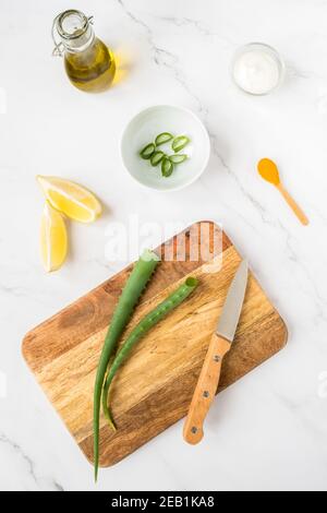 Hausgemachtes Hautpflegekonzept. Grüne natürliche Inhaltsstoffe Aloe Vera, Zitrone, Joghurt, Kurkuma, Olivenöl für die Herstellung einer kosmetischen Maske auf einem hellen Hintergrund Stockfoto