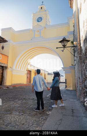 Junges hispanische Paar, das Hand in Hand unter dem Bogen läuft Von Santa Catalina in Antigua Guatemala - Touristen in wichtigen avenue des kolonialen Guatemala Stockfoto