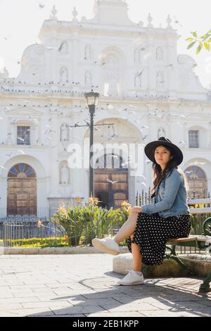 Junge hispanische Frau, die vor dem San Jose sitzt kathedrale in Antigua Guatemala - Touristen reisen in kolonialen Stadt - Frau im zentralen Park Stockfoto