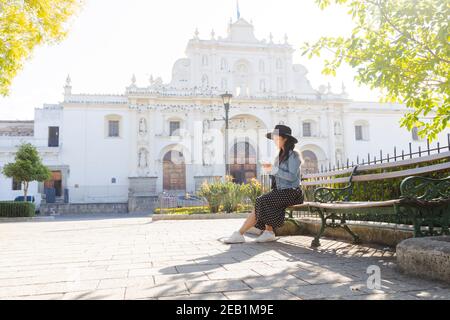 Junge hispanische Frau, die vor ihrem Telefon sitzt Die San Jose Kathedrale in Antigua Guatemala-Touristen Reisen in kolonialen Stadtfrau in Th Stockfoto