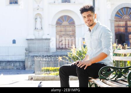 Lächelnder junger Mann, der vor dem San Jose sitzt kathedrale in Antigua Guatemala - junge Touristen genießen seinen Urlaub In der Kolonialstadt - zentral Stockfoto