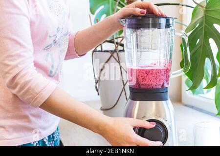 Eine Frau mischt Beerenmoothie in einem Mixer. Das Konzept eines gesunden Lebensstils. Stockfoto