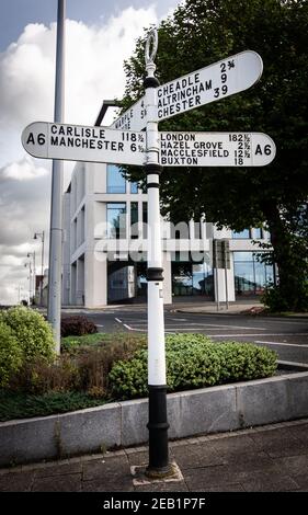 Ein altes Straßenschild (Fingerpost/Wegweiser), das an der Kreuzung neben dem Rathaus von Stockport den Weg/die Entfernung angibt. England, Großbritannien Stockfoto